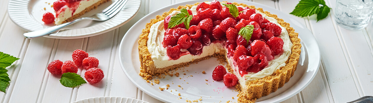 Raspberry cream cheese pie with 2 slices cut out, and 2 peices of pie on white plates.